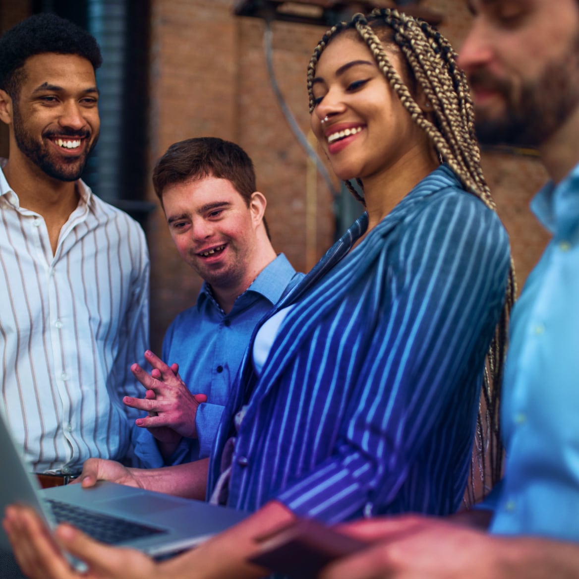 a group of individuals smiling and looking at a laptop